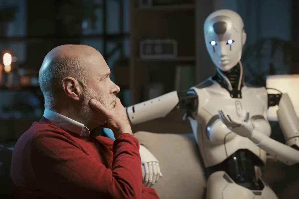 Hombre mayor pensativo sentado en el sofá junto a un robot humanoide doméstico